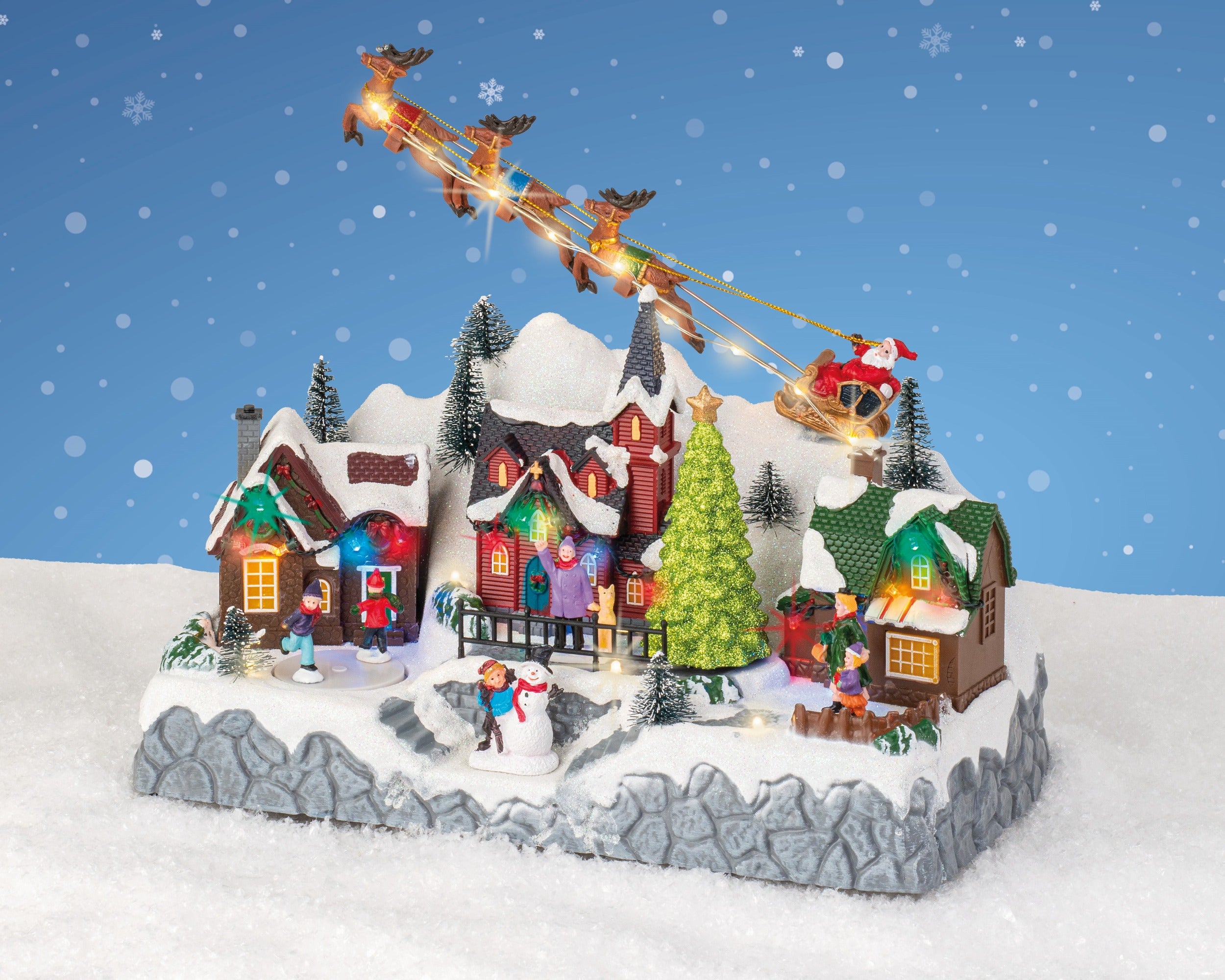 Kaemingk, Villaggio Natalizio Slitta con Renne 32x17x28 cm, ambientazione Lemax con casette illuminate, albero di Natale, pupazzo di neve e Babbo Natale sulla slitta trainata da renne in volo - DeMatteis.it