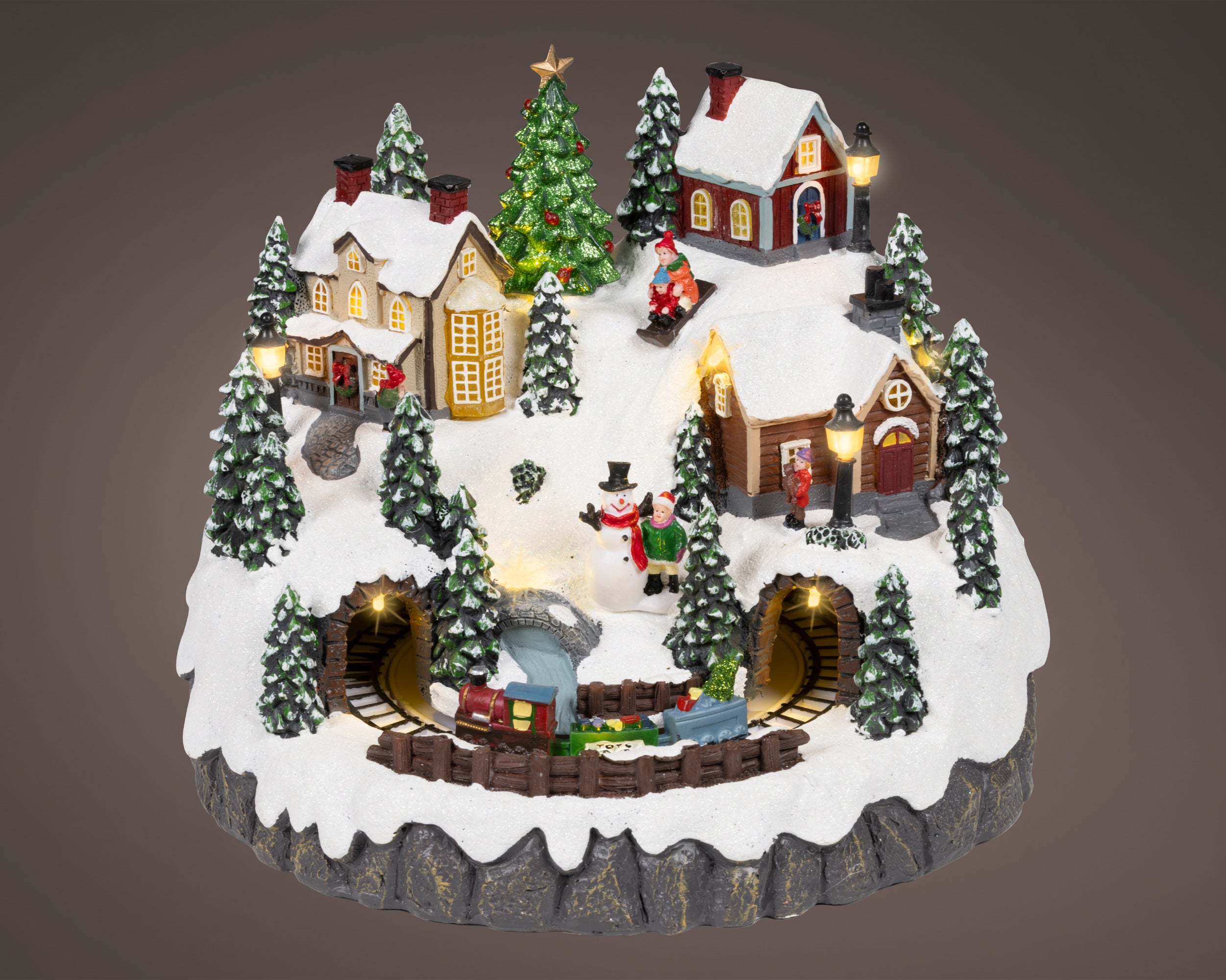 Kaemingk, Villaggio Innevato con Treno in Movimento 27x29x24 cm, ambientazione natalizia illuminata con casette, alberi innevati, pupazzo di neve e trenino su binari in galleria - DeMatteis.it