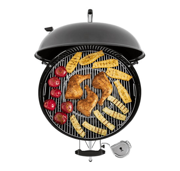 Weber, Barbecue Master Touch 57 Smoke Grey con cupola grigia aperta che mostra griglia circolare con carne, salsicce e verdure in cottura - DeMatteis.it