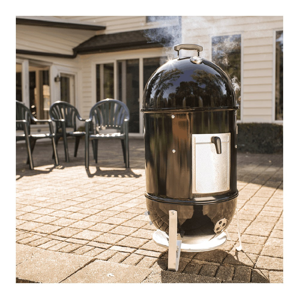 Weber, Affumicatore Smokey Mountain con corpo nero lucido, coperchio a cupola, sportello di accesso frontale e base bianca su terrazza esterna - DeMatteis.it