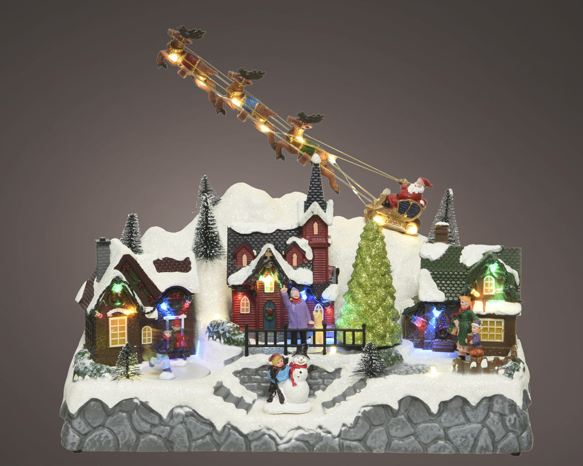 Kaemingk, Villaggio Natalizio Slitta Con Renne 32x17x28 cm con Babbo Natale in volo, casette innevate illuminate a LED, pupazzo di neve e personaggi in miniatura - DeMatteis.it