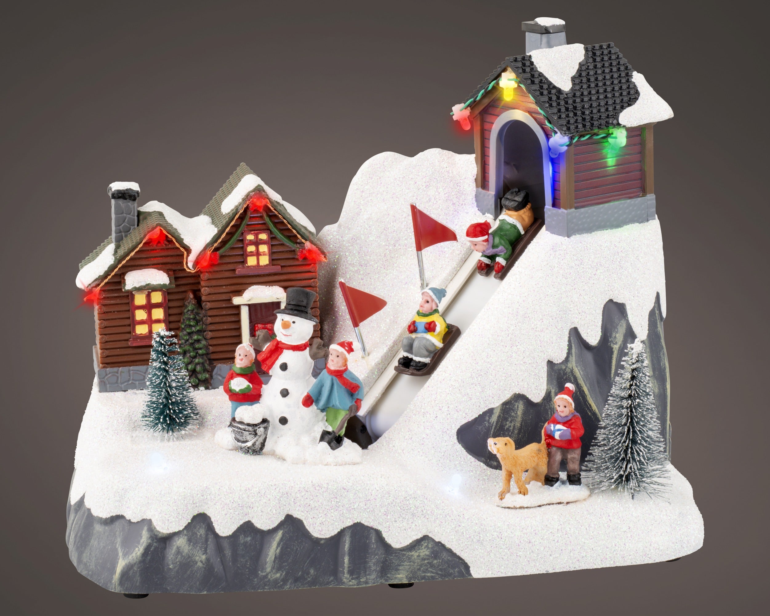 Kaemingk, Villaggio Sciatori 13x22x17 cm, ambientazione natalizia Lemax con casette innevate, pupazzo di neve, bambini sulla pista da slittino e luci LED integrate - DeMatteis.it