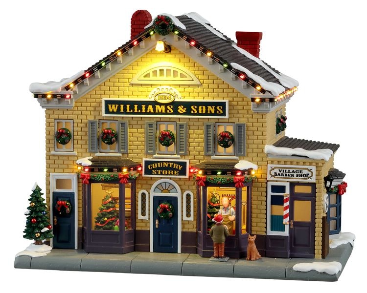Williams & Sons Country Store Lemax: negozio del villaggio natalizio con mattoni gialli, decorazioni rosse, luci colorate e bambino con cane davanti alla vetrina - Dematteis.it