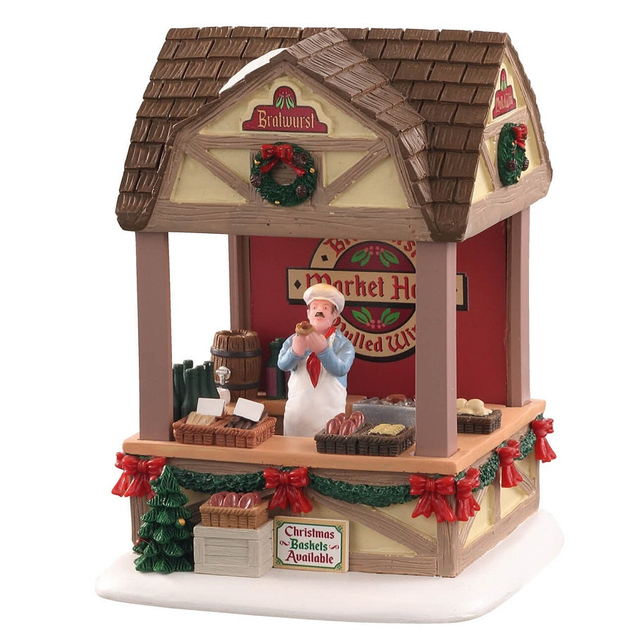 Christmas Market Bratwurst Lemax bancarella natalizia tedesca con venditore, tetto in legno marrone, decorazioni festive rosse e verdi per villaggio Lemax Caddington. | Dematteis.it