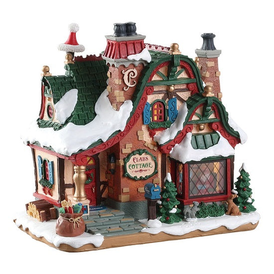The Claus Cottage Lemax illuminato con tegole verdi e dettagli rossi, perfetto Cottage di Babbo Natale per Villaggio Lemax innevato con accessori decorativi. | Dematteis.it