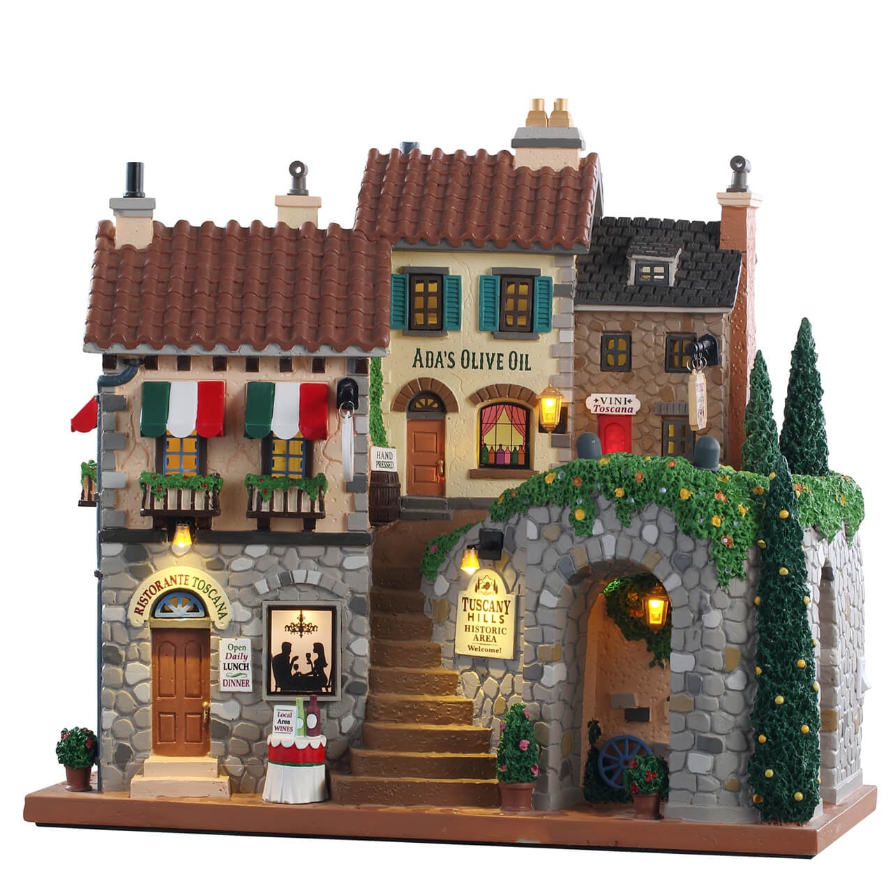 Tuscany Hills Lemax villaggio miniatura con negozi toscani illuminati, tetti in tegole rosse, balconi con tende tricolori e vegetazione mediterranea per collezioni natalizie. | Dematteis.it